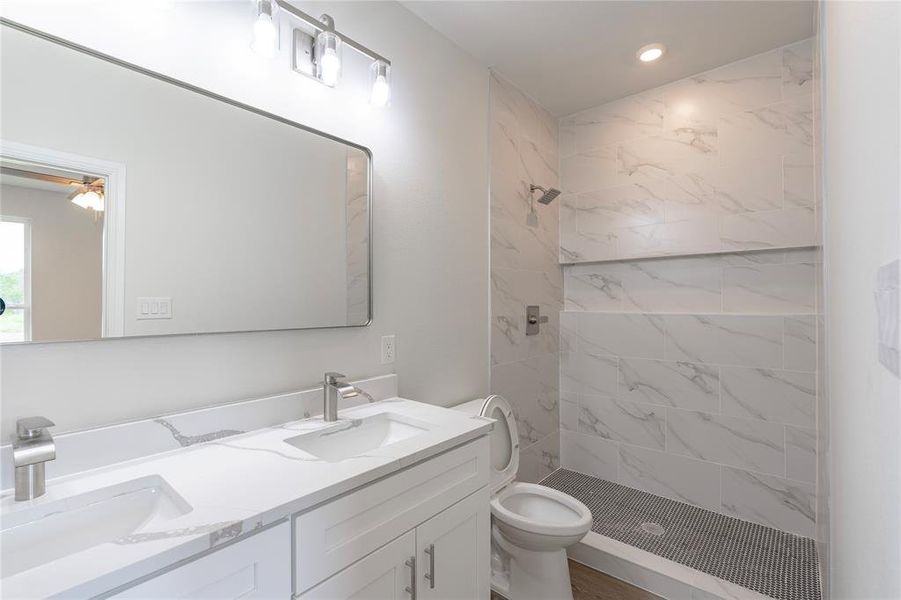 Bathroom featuring vanity, toilet, and a tile shower