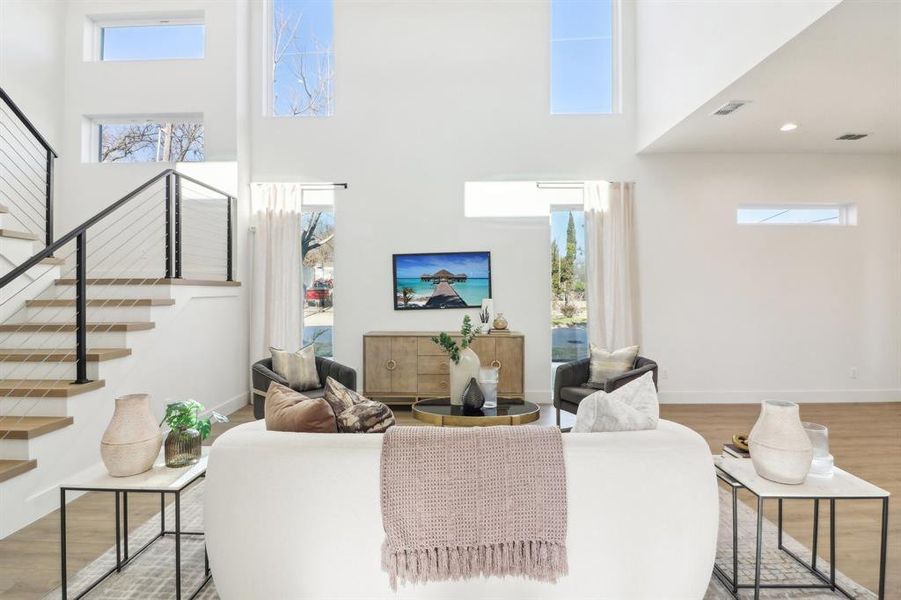 Living room with a towering ceiling and light hardwood / wood-style floors