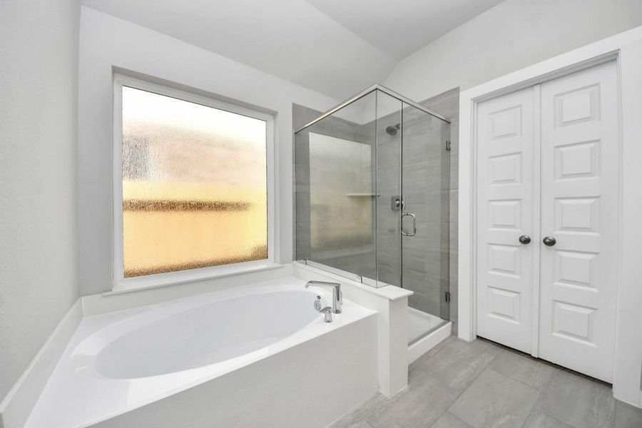 Indulge in a spa-like retreat within the confines of this primary bathroom. Delight in a spacious walk-in shower enveloped in stylish tile surround, unwind in a separate garden tub adorned with custom detailing. Sample photo of completed home with similar floor plan. Actual colors and selections may vary. Indulge in a spa-like retreat within the confines of this primary bathroom. Delight in a spacious walk-in shower enveloped in stylish tile surround, unwind in a separate garden tub adorned with custom detailing. Sample photo of completed home with similar floor plan. Actual colors and selections may vary.