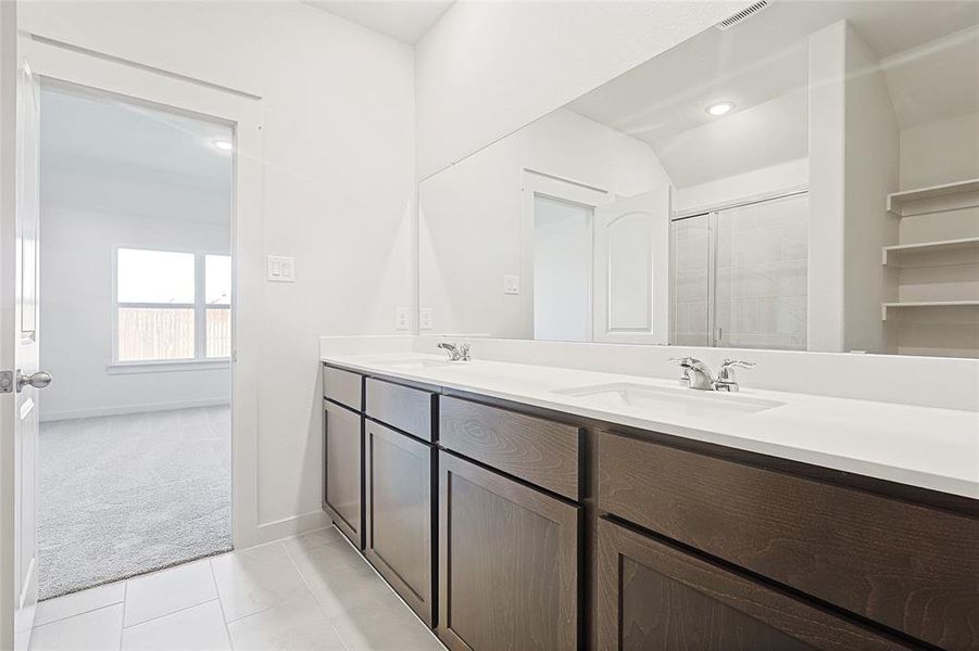 Bathroom featuring tile patterned flooring, vanity, and a shower with door