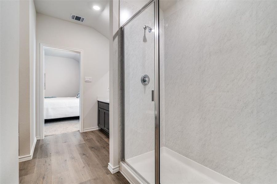 Ensuite bathroom with a shower stall, visible vents, wood finished floors, and vanity