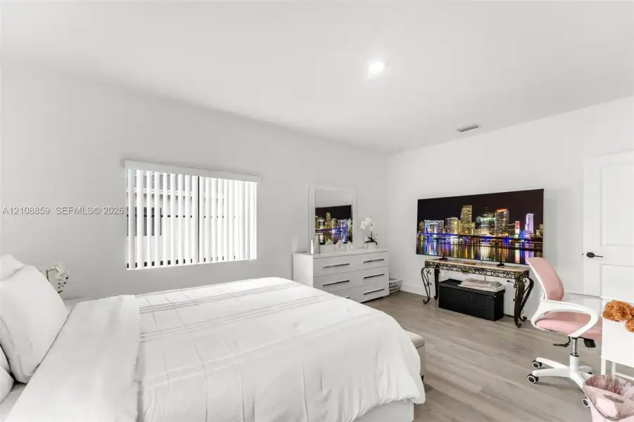 Spacious interior featuring wood-finish flooring, smooth ceilings with recessed lighting, and vertical blinds