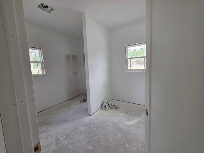 Interior space featuring two windows, an unfinished concrete floor, and white walls