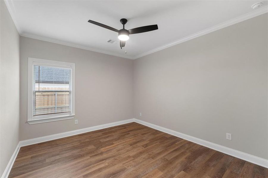 Unfurnished room featuring a ceiling fan, baseboards, ornamental molding, and wood finished floors