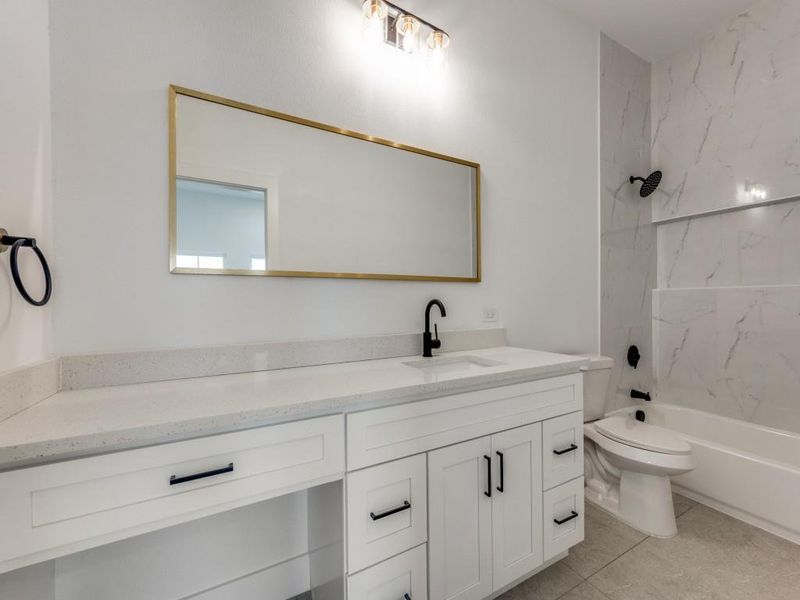 Full bathroom with tile patterned flooring, vanity, tiled shower / bath combo, and toilet