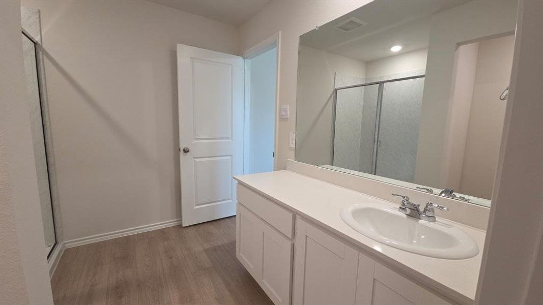 Bathroom vanity featuring an integrated oval sink, chrome faucet, and expansive wall-mounted mirror