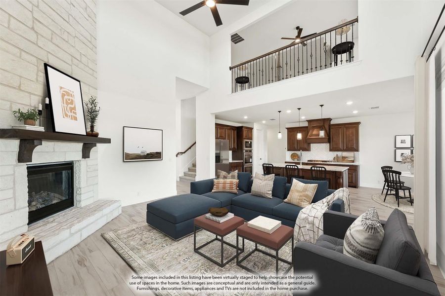 Open-concept living room with two-story ceiling, stone fireplace, and view of kitchen and upstairs loft. Open-concept living room with two-story ceiling, stone fireplace, and view of kitchen and upstairs loft.