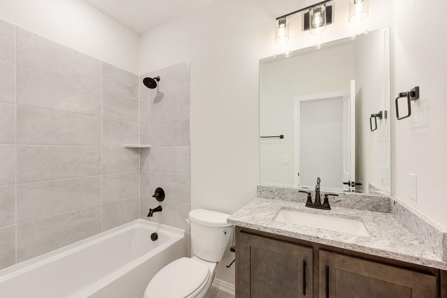 Full bathroom with tiled tub-shower combo, wood vanity with granite countertop, and dark bronze fixtures Full bathroom with tiled tub-shower combo, wood vanity with granite countertop, and dark bronze fixtures