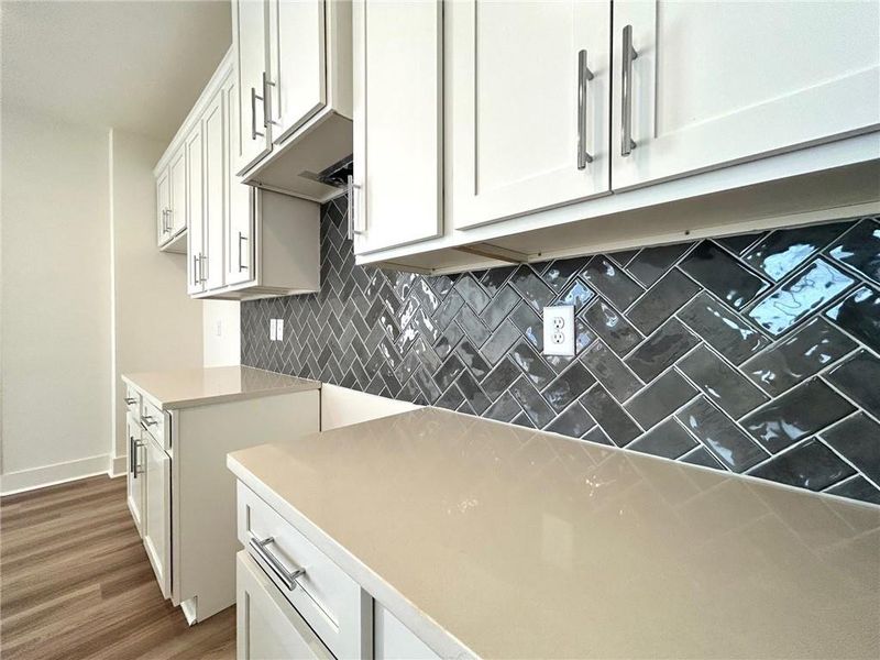 Kitchen featuring dark wood-type flooring, white cabinets, and tasteful backsplash