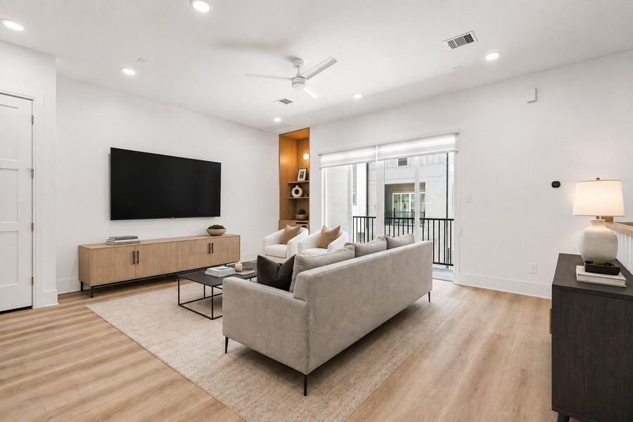Natural light and clean sightlines define the living space, while sliding glass doors open to a private paved balcony, extending the home's sense of openness beyond its walls.