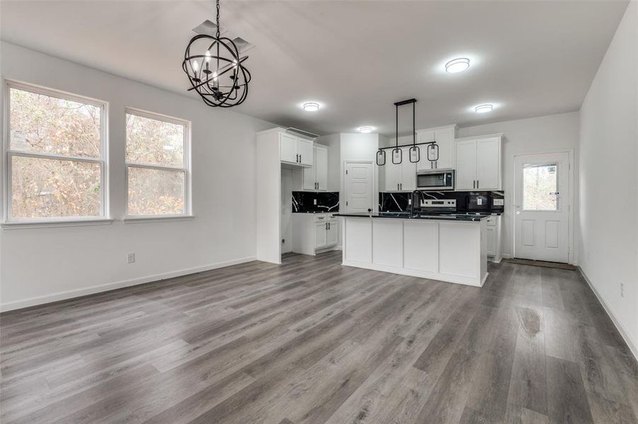 Kitchen featuring hanging light fixtures, an inviting chandelier, a kitchen island, light hardwood / wood-style flooring, and white cabinets