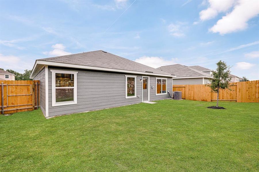 Back of property with a fenced backyard and roof with shingles