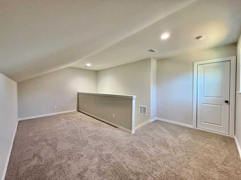 Spare room featuring light colored carpet and lofted ceiling