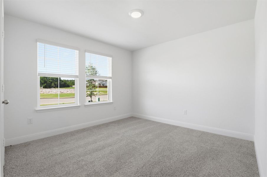 Bright interior room featuring a light gray carpet, white walls, and two windows with white blinds