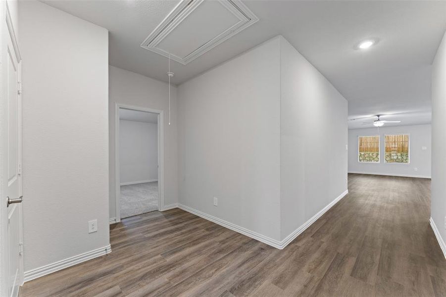Hallway featuring attic access and wood finished floors Hallway featuring attic access and wood finished floors