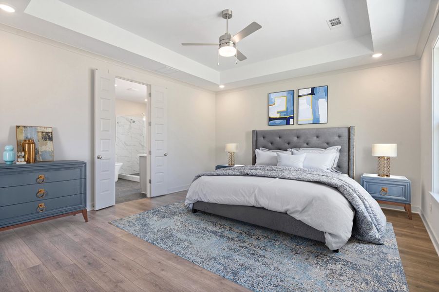 Bedroom featuring recessed lighting, a raised ceiling, wood finished floors, a ceiling fan, and ensuite bathroom