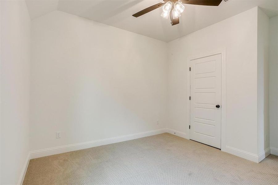 Spare room with light carpet, ceiling fan, and vaulted ceiling