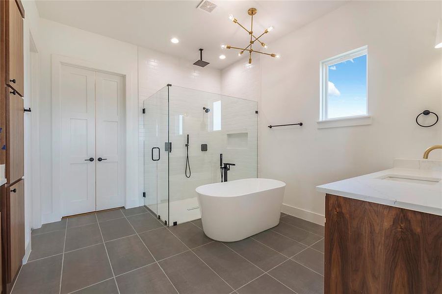 Bathroom with tile patterned flooring, vanity, a chandelier, and plus walk in shower