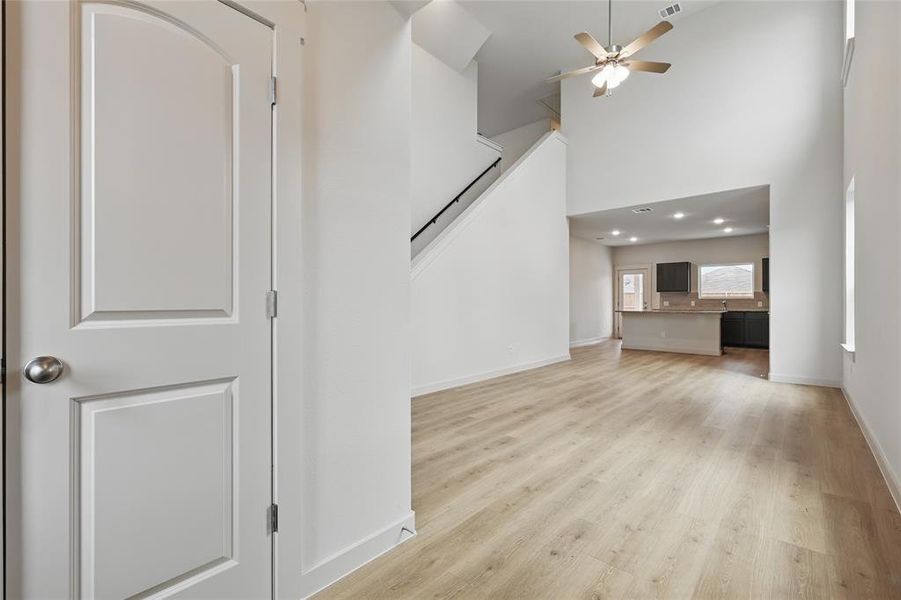 Unfurnished living room featuring a ceiling fan, a high ceiling, light wood-style floors, and recessed lighting