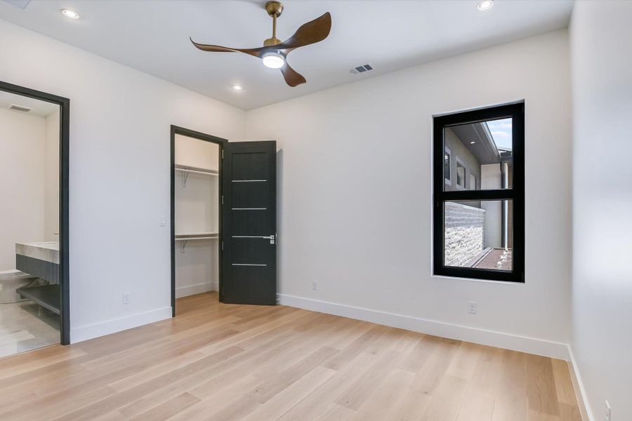 Guest bedroom with light wood flooring, a spacious closet, recessed lighting, ensuite bathroom, and a closet Guest bedroom with light wood flooring, a spacious closet, recessed lighting, ensuite bathroom, and a closet