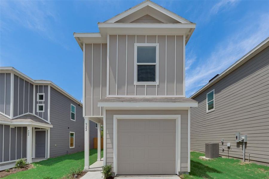 View of front facade featuring a garage, a front lawn, and central AC unit