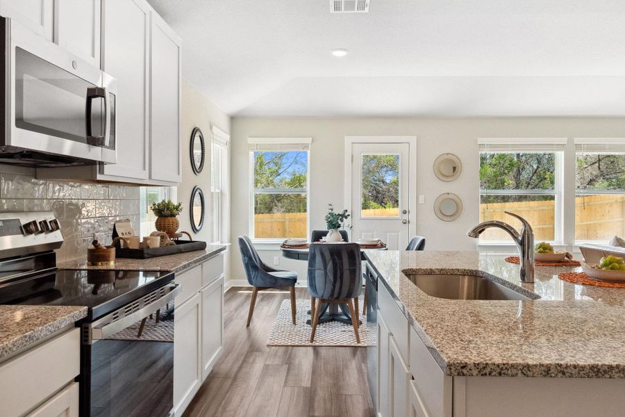 Kitchen featuring stainless steel appliances, white cabinetry, light stone counters, dark wood finished floors, and tasteful backsplash Kitchen featuring stainless steel appliances, white cabinetry, light stone counters, dark wood finished floors, and tasteful backsplash