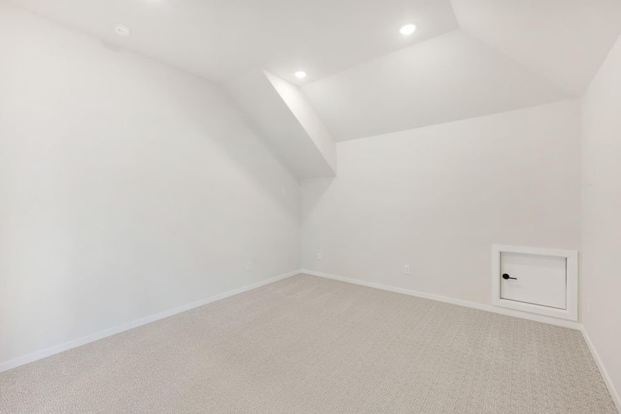 Empty bonus room with sloped ceiling, carpet flooring, recessed lights, and small access door on wall