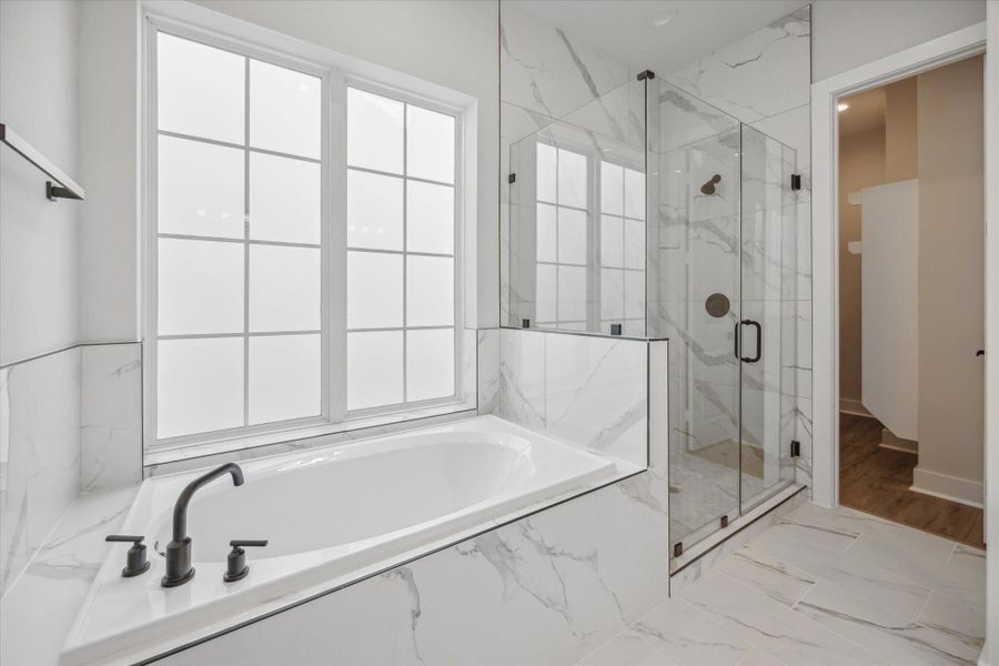 This primary bathroom offers a soaking tub, a large glass shower, double vanities and walk-in closet