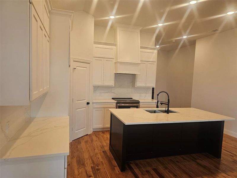 Kitchen featuring white cabinetry, sink, a center island with sink, and stainless steel electric stove