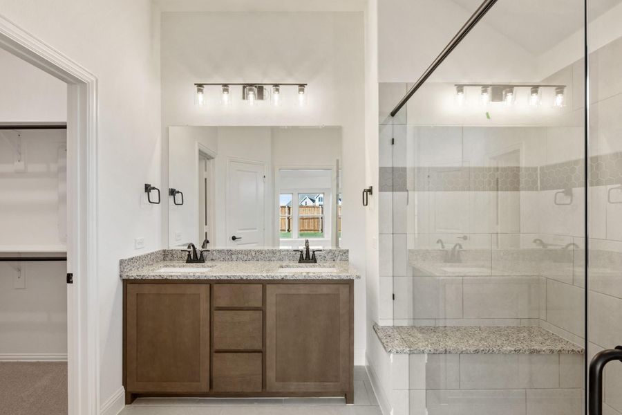 Bathroom with double vanity, granite countertop, wood cabinets, and glass-enclosed tiled shower with bench seat Bathroom with double vanity, granite countertop, wood cabinets, and glass-enclosed tiled shower with bench seat