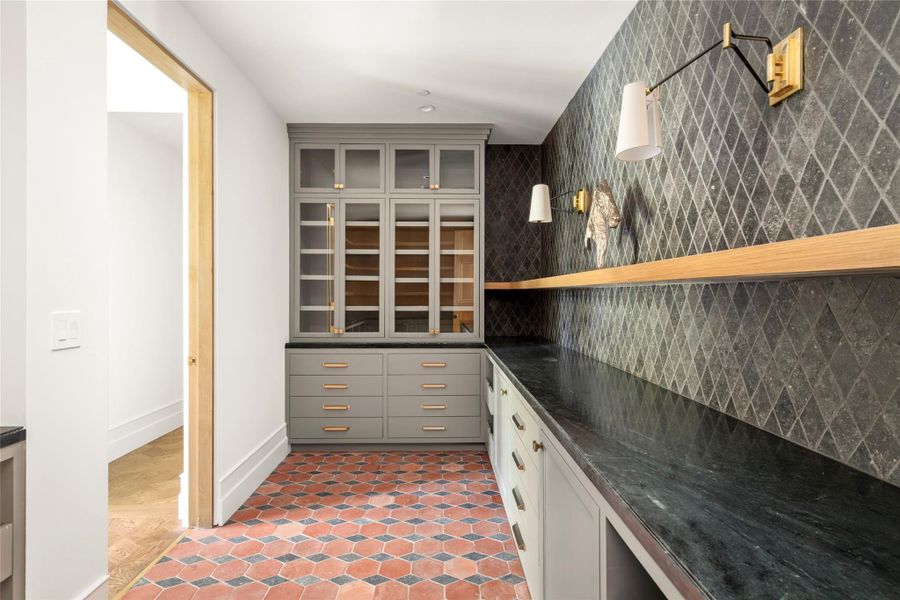 The expansive butler’s pantry is designed as a beautiful extension of the kitchen, with custom cabinetry, generous prep space, natural stone countertops, and richly patterned stone flooring. Thoughtfully positioned just off the dining room, it provides discreet space for prep, serving, and entertaining. The expansive butler’s pantry is designed as a beautiful extension of the kitchen, with custom cabinetry, generous prep space, natural stone countertops, and richly patterned stone flooring. Thoughtfully positioned just off the dining room, it provides discreet space for prep, serving, and entertaining.