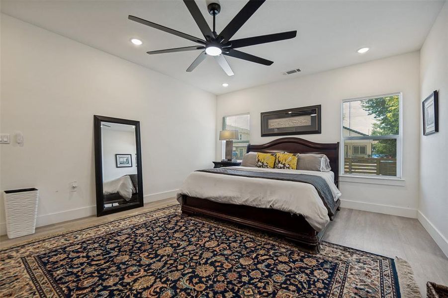 Spacious room featuring light wood-finish flooring, recessed lighting, and a modern black ceiling fan Spacious room featuring light wood-finish flooring, recessed lighting, and a modern black ceiling fan