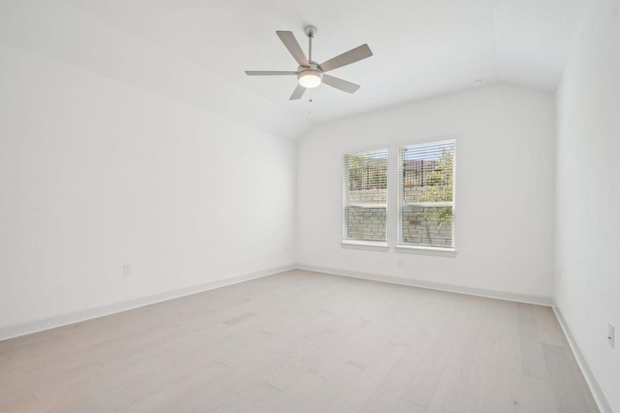 Empty room featuring vaulted ceiling, light wood-type flooring, and ceiling fan Empty room featuring vaulted ceiling, light wood-type flooring, and ceiling fan