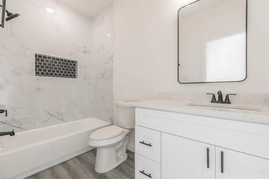 Full bath with shower / bath combination, vanity, toilet, and wood finished floors