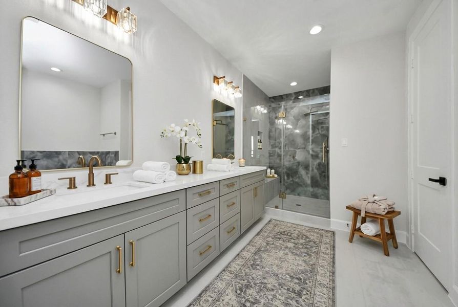 Spa-inspired primary bathroom featuring a freestanding soaking tub, oversized glass-enclosed shower, designer tile accents, and elegant gold fixtures for a true retreat experience.