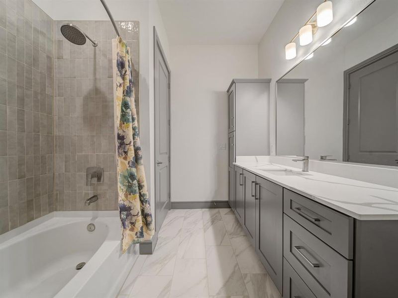 Bathroom with shower / bath combo, vanity, and light marble finish floors