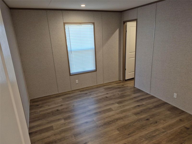 Unfurnished bedroom featuring dark wood finished floors and a decorative wall