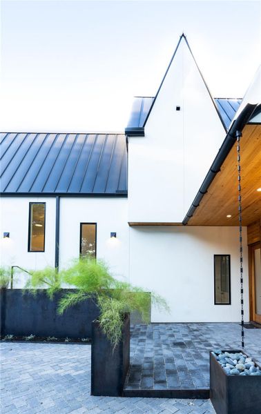 View of side of property featuring a standing seam roof, stucco siding, and a patio area