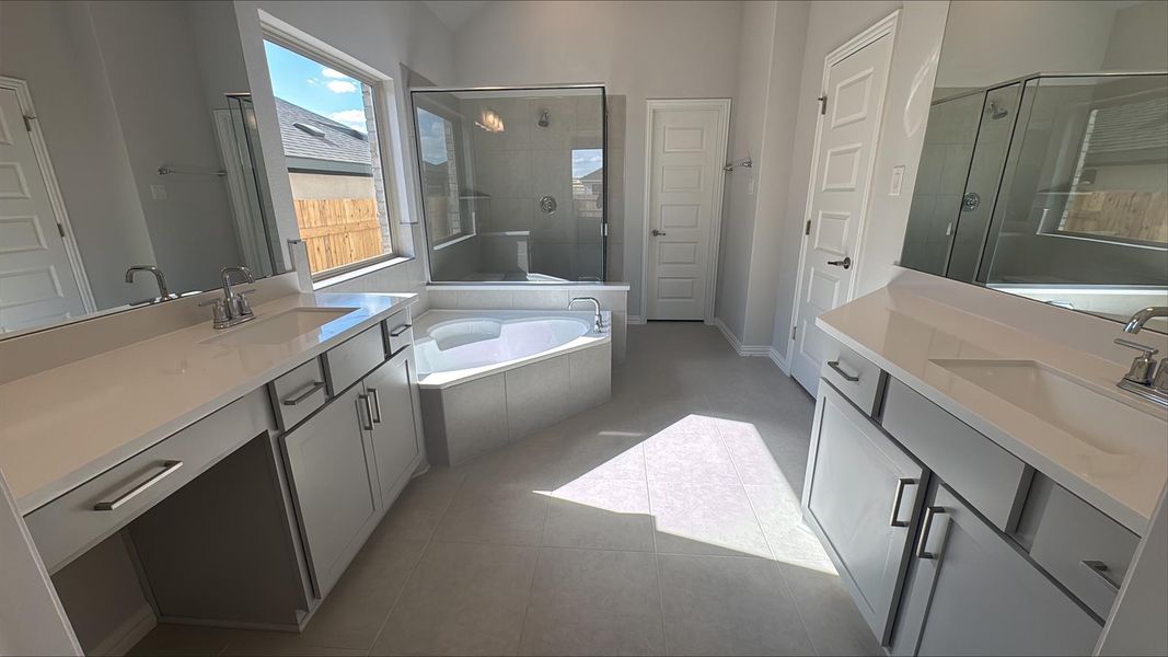 Full bathroom featuring a garden tub, two vanities, a shower stall, and light tile patterned floors Full bathroom featuring a garden tub, two vanities, a shower stall, and light tile patterned floors