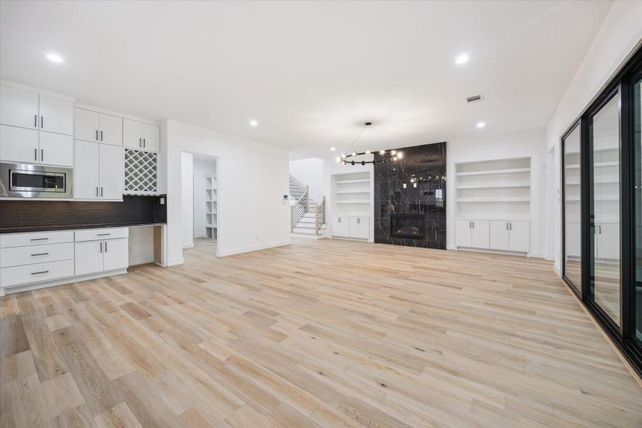 Tucked just off the main living space, a built-in bar with wine storage, custom cabinetry, and sleek tile backsplash creates the perfect setup for entertaining. The open layout seamlessly connects to the fireplace feature wall and backyard views beyond the sliding glass doors. Tucked just off the main living space, a built-in bar with wine storage, custom cabinetry, and sleek tile backsplash creates the perfect setup for entertaining. The open layout seamlessly connects to the fireplace feature wall and backyard views beyond the sliding glass doors.