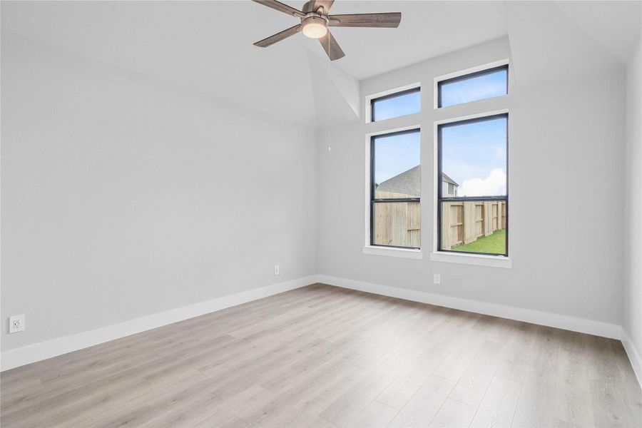 Retreat to this bright and airy primary bedroom, a serene sanctuary designed for ultimate relaxation and comfort. Vaulted ceilings, large windows, laminate flooring, and modern ceiling fan give this room a peaceful space to come home to.