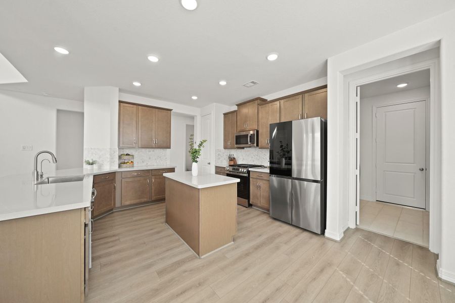 Timeless wood-stained cabinetry with abundant storage, with a laundry room located on the right.