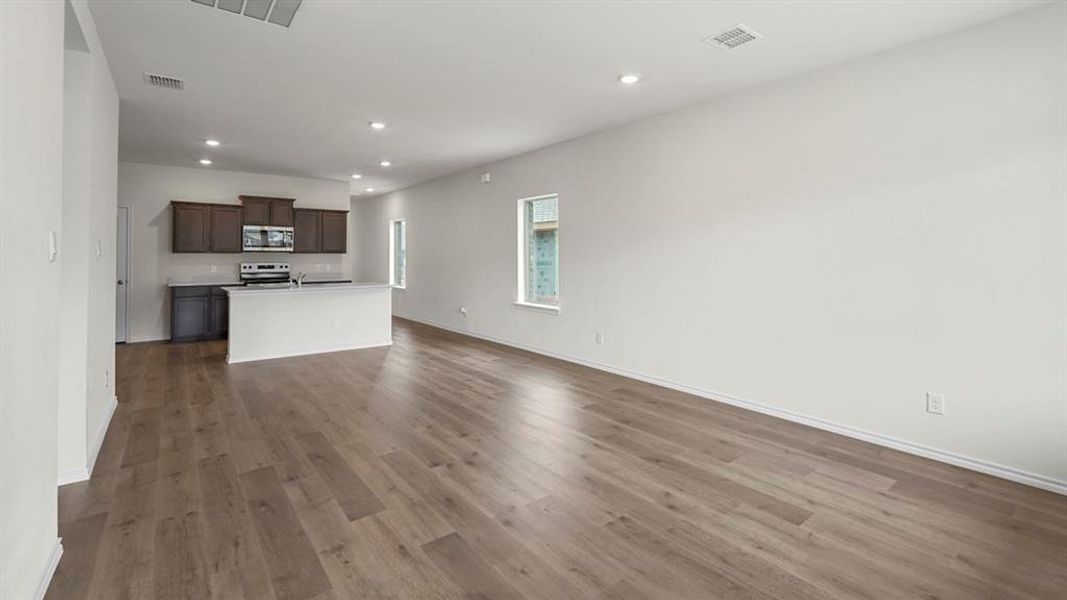 Open-concept living space featuring wood-finish flooring, recessed lighting, and white baseboards