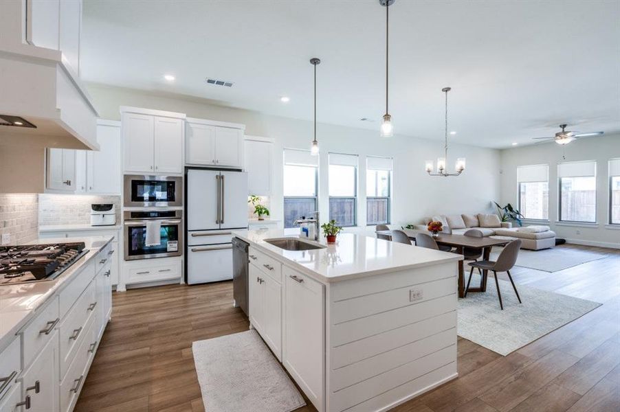 Kitchen with white cabinets, pendant lighting, backsplash, appliances with stainless steel finishes, and recessed lighting Kitchen with white cabinets, pendant lighting, backsplash, appliances with stainless steel finishes, and recessed lighting