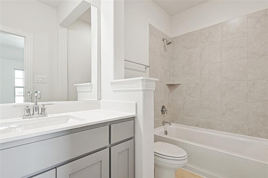 Full bathroom with vanity, tiled shower / bath, and toilet