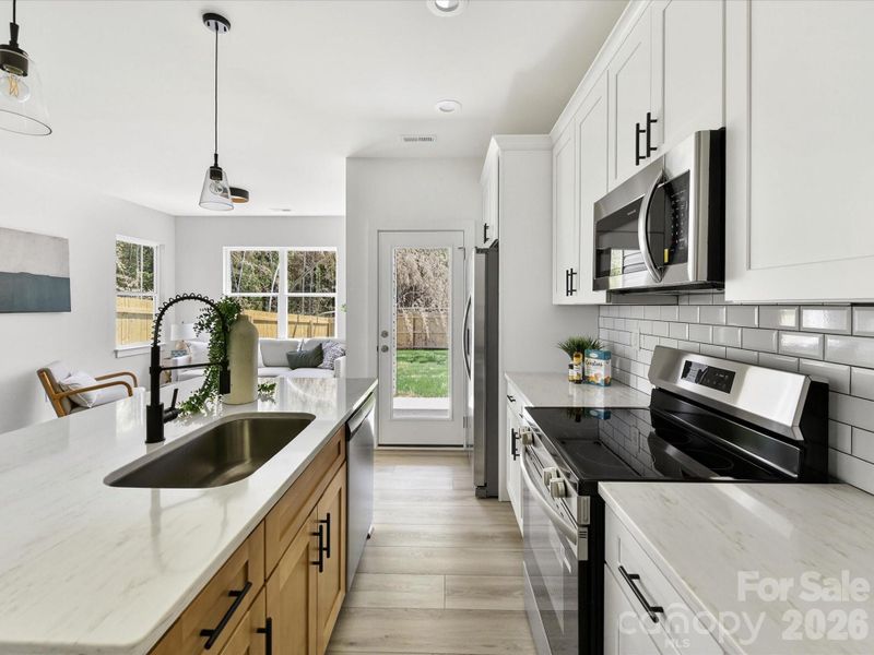 Bright, open-concept kitchen featuring a spacious island with seating, stainless steel appliances, and seamless flow into the sun-filled living area.