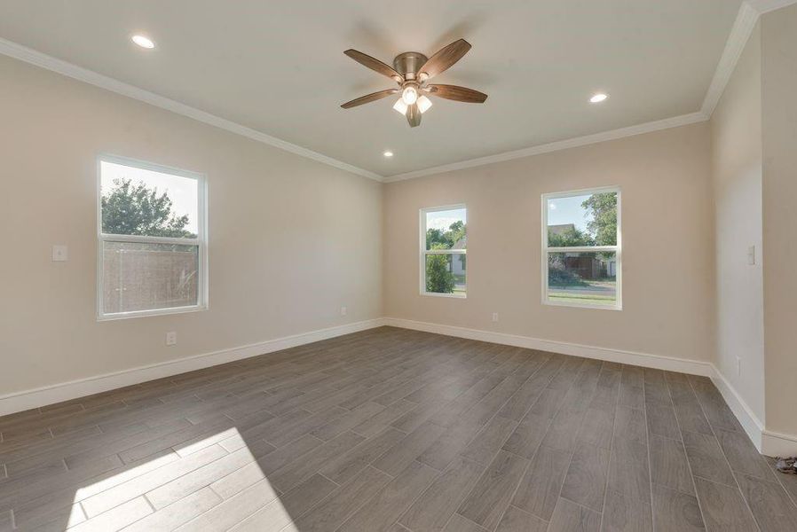 Unfurnished room with plenty of natural light, ceiling fan, crown molding, and wood-type flooring