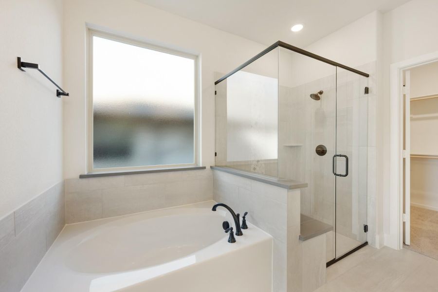 Ensuite bathroom with soaking tub, glass walk-in shower, and walk-in closet entrance Ensuite bathroom with soaking tub, glass walk-in shower, and walk-in closet entrance