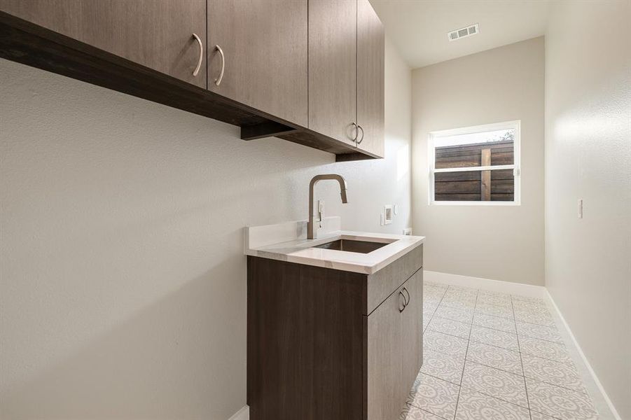 Laundry room with hookup for a washing machine, cabinets, light tile patterned floors, and sink