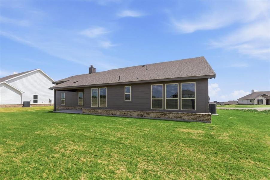 Rear view of house with a patio, brick siding, a yard, and a chimney